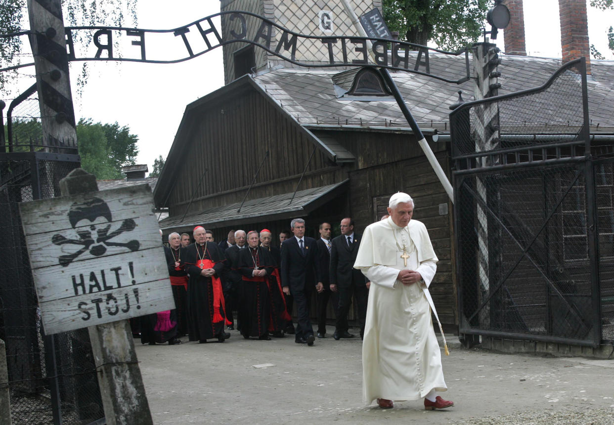 FILE - Pope Benedict XVI walks through the gate of the former Nazi concentration camp of Auschwitz, with sign above reading in German "Work will set you free", in Oswiecim, Poland, on May 28, 2006. Pope Emeritus Benedict XVI, the German theologian who will be remembered as the first pope in 600 years to resign, has died, the Vatican announced Saturday. He was 95. (AP Photo/Diether Endlicher, File)