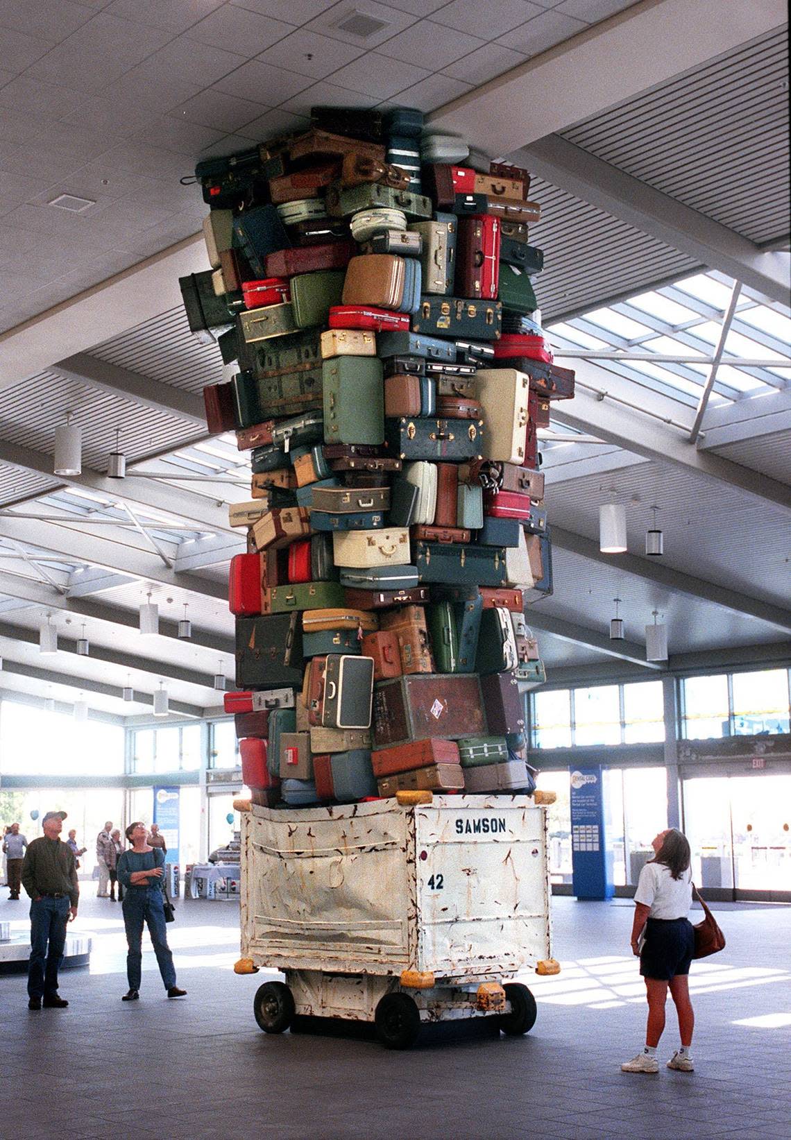 Folks stop in amusement and admiration in 1998 to view “Samson,” one of two similar suitcase sculptures by artist Brian Goggin that greet travelers in the baggage claim area of Terminal A at Sacramento International Airport.