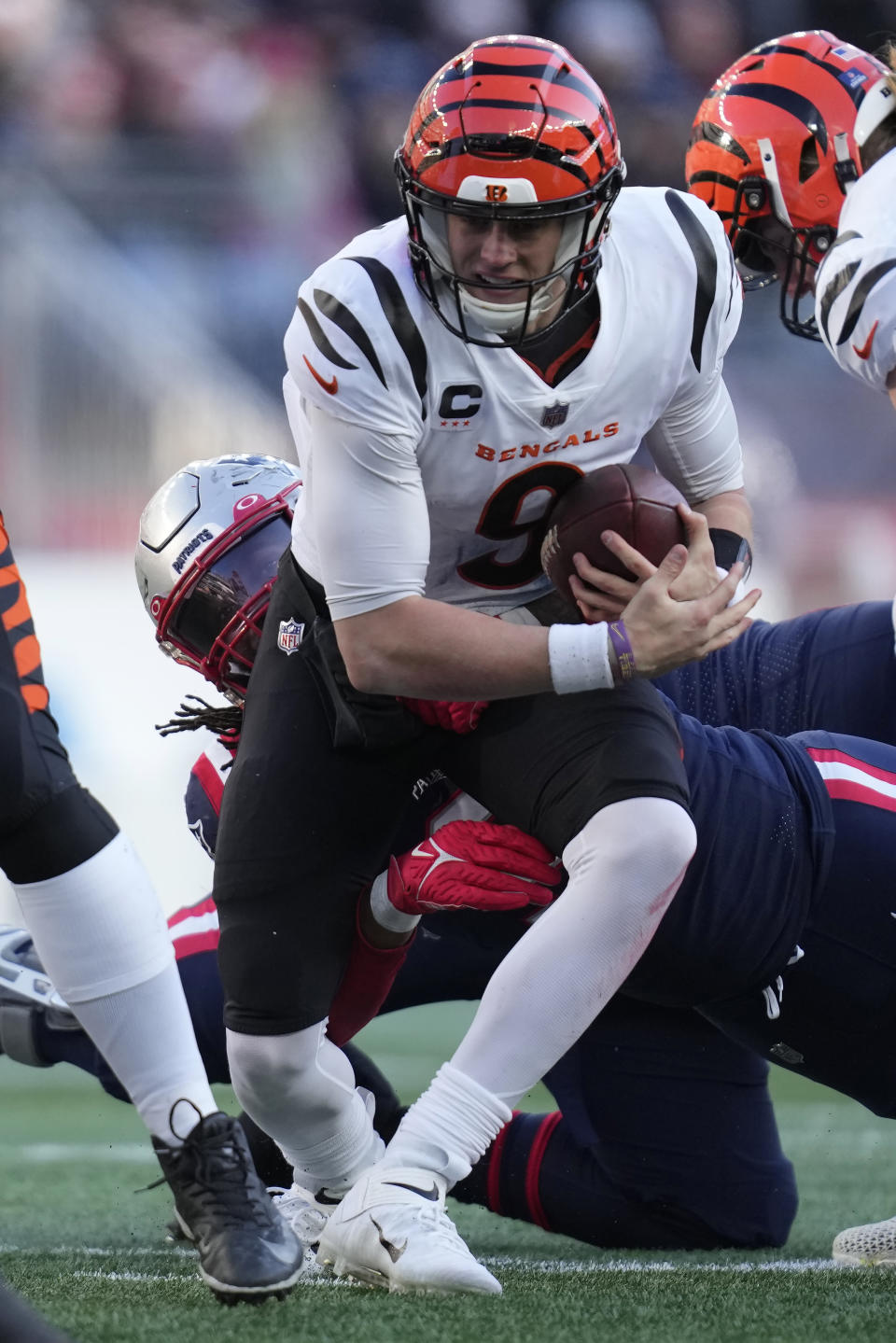 Cincinnati Bengals quarterback Joe Burrow (9) is brought down by New England Patriots linebacker Matthew Judon, behind, during the first half of an NFL football game, Saturday, Dec. 24, 2022, in Foxborough, Mass. (AP Photo/Charles Krupa)