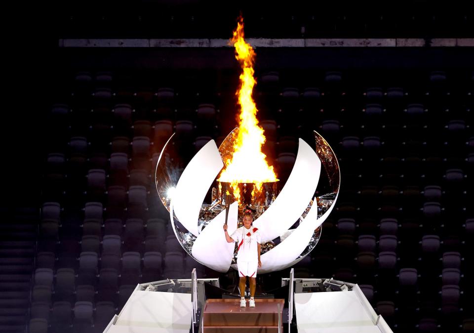 Naomi Osaka of Team Japan lights the Olympic cauldron with the Olympic torch during the opening ceremony at an empty Olympic Stadium.