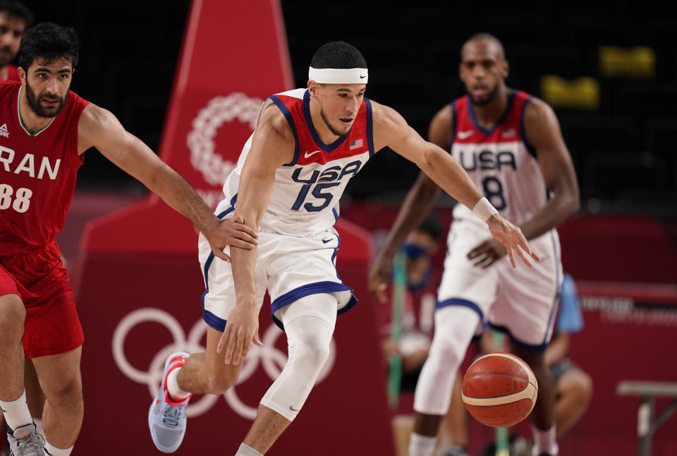 United States' Devin Booker (15), center, steals the ball from Iran's Behnam Yakhchalidehkordi (88), left, during men's basketball preliminary round game at the 2020 Summer Olympics, Wednesday, July 28, 2021, in Saitama, Japan. (AP Photo/Charlie Neibergall)