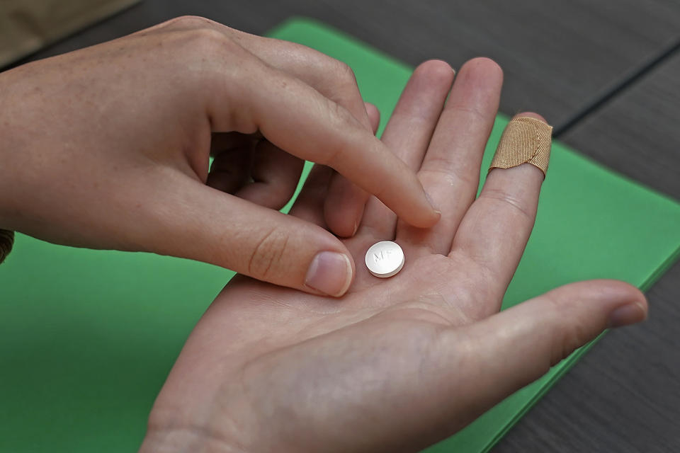 FILE - A patient prepares to take the first of two combination pills, mifepristone, for a medication abortion during a visit to a clinic in Kansas City, Kan., on Wednesday, Oct. 12, 2022. The Supreme Court is facing a self-imposed Friday, April 21, 2023, night deadline to decide whether women’s access to a widely used abortion pill will stay unchanged until a legal challenge to its Food and Drug Administration approval is resolved. The justices are weighing arguments that allowing restrictions contained in lower-court rulings to take effect would severely disrupt the availability of the drug, mifepristone, which is used in the most common abortion method in the United States. (AP Photo/Charlie Riedel, File)