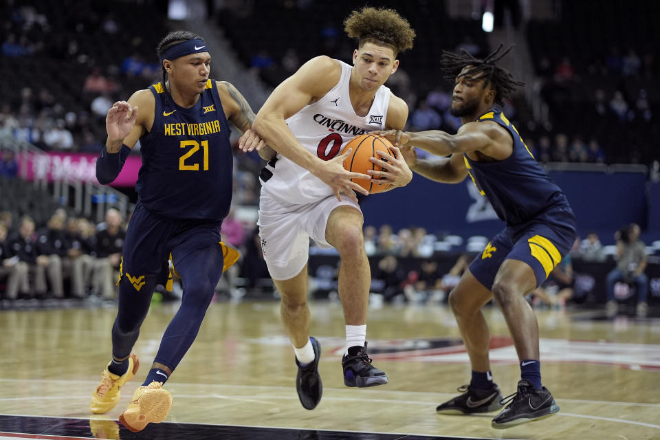 Cincinnati guard Dan Skillings Jr. (0) drives under pressure from West Virginia guards RaeQuan Battle (21) and Kobe Johnson (2) during the second half of an NCAA college basketball game Tuesday, March 12, 2024, in Kansas City, Mo. Cincinnati won 90-85. (AP Photo/Charlie Riedel)