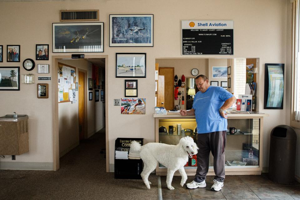 Manager Paul Turner leans against the front desk of the Maury County Airport lobby in Mount Pleasant, Tenn. on Wednesday, June 14, 2023. His dog Bella is in tow.