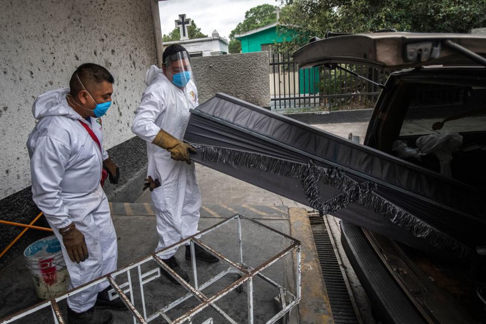 Los trabajadores se afanan en descargar el ataúd de un fallecido que va a ser cremado. La actividad en los últimos días es frenética debido a la expansión del virus por México. (Photo by PEDRO PARDO/AFP via Getty Images)