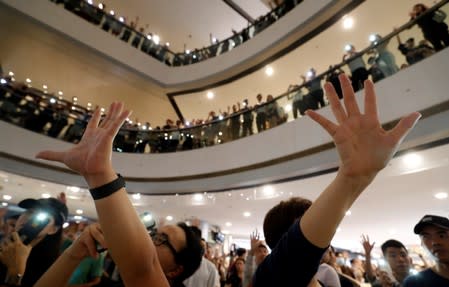 People raise their hands as they hold their mobile phones with torch light on during a protest at International Finance Center (IFC) in Hong Kong