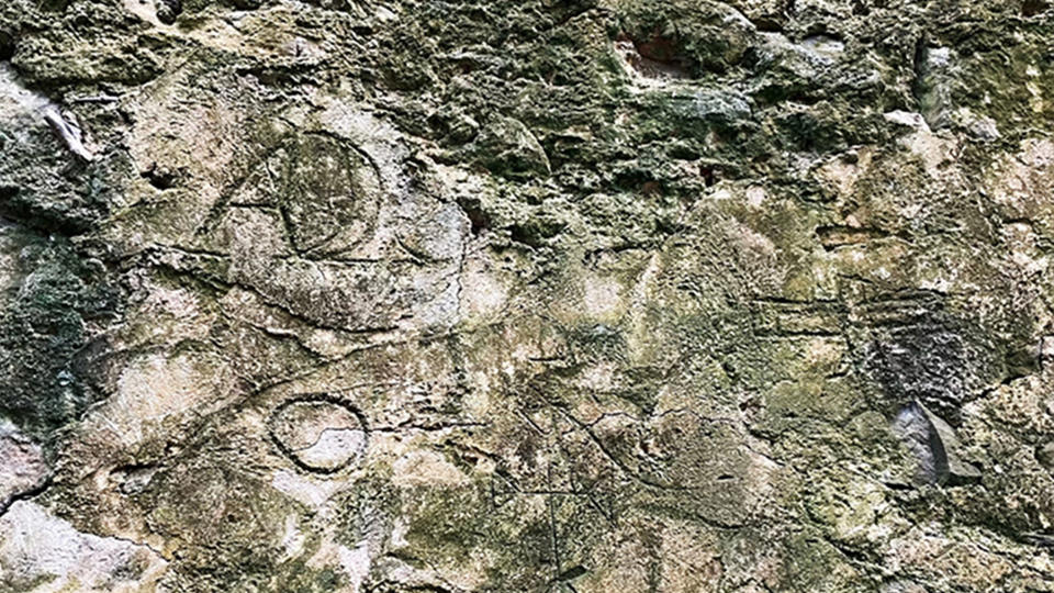 A old stone wall displays graffiti from the slave trade era.