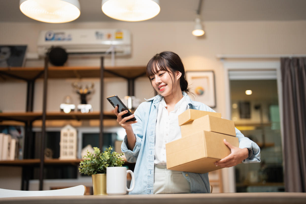 Beautiful Young Woman With Smartphone Receiving Parcel Purchased Online