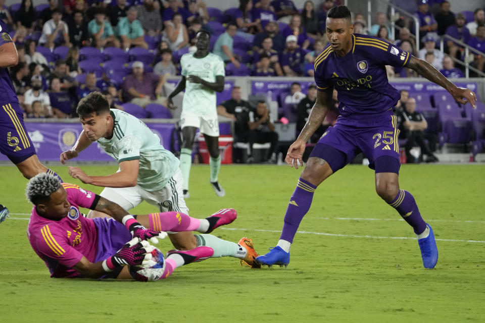 Orlando City goalkeeper Pedro Gallese, left, blocks a shot by Atlanta United forward Miguel Berry, center, as Orlando City defender Antonio Carlos (25) comes in to assist during the second half of an MLS soccer match, Saturday, May 27, 2023, in Orlando, Fla. (AP Photo/John Raoux)
