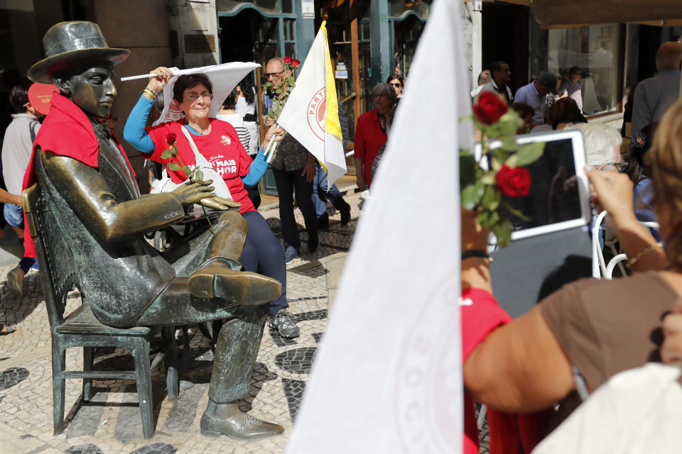 A Socialist Party supporter has her picture taken by the statue of Portuguese poet Fernando Pessoa while waiting for the arrival of Prime Minister and Socialist Party leader Antonio Costa for an election campaign action in downtown Lisbon Friday, Oct. 4, 2019. Portugal will hold a general election on Oct. 6 in which voters will choose members of the next Portuguese parliament. The ruling Socialist Party hopes an economic recovery during its four years of governing will persuade voters to return the party to power. (AP Photo/Armando Franca)