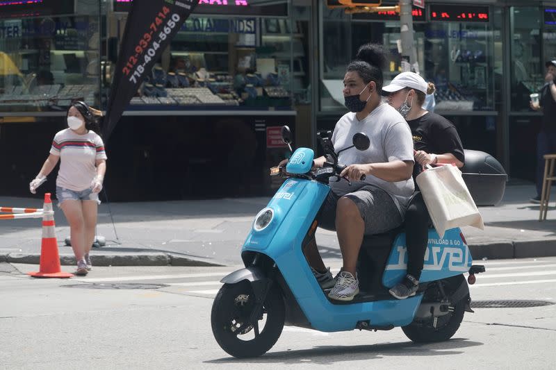 People ride a Revel scooter while not wearing helmets in the Manhattan borough of New York City