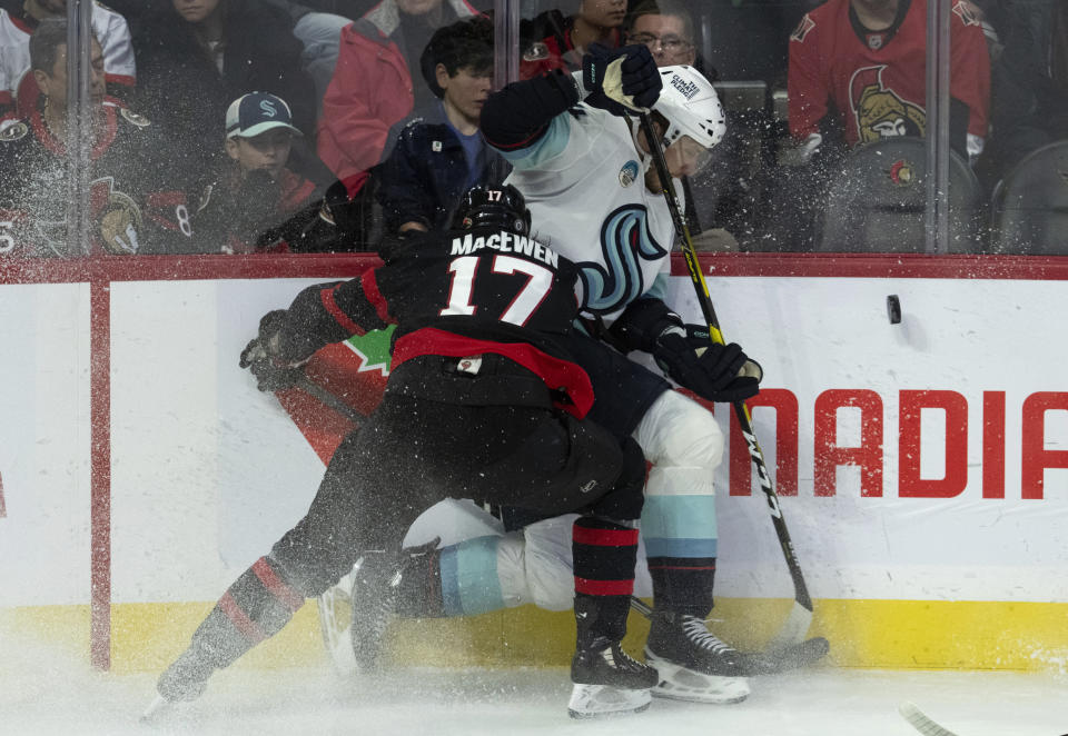 Ottawa Senators center Zack MacEwen (17) ties up Seattle Kraken defenseman Jamie Oleksiak, right, along the boards during first-period NHL hockey game action, Saturday, Dec. 2, 2023, in Ottawa, Ontario. (Adrian Wyld/The Canadian Press via AP)