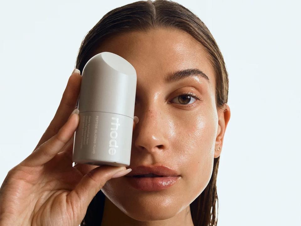 Hailey Bieber holding a glazing peptide serum from her company Rhode