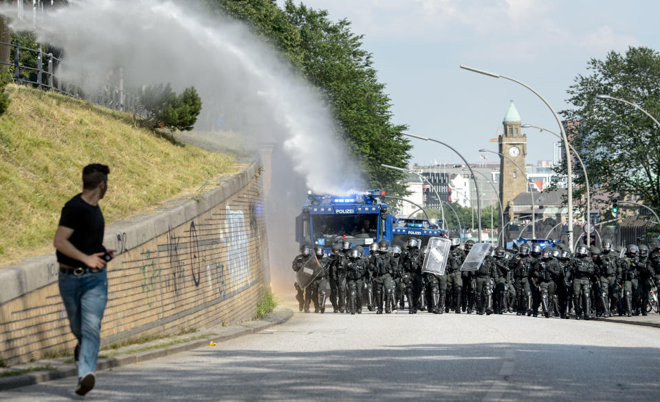 An anti-G-20 Summit demonstrator runs away from a police water cannon.