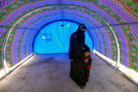 A displaced Iraqi woman, who fled a village controlled by Islamic State militants, stands with her child inside her tent at the refugee camp in Hammam Ali, south of Mosul, Iraq February 24, 2017. REUTERS/Alaa Al-Marjani