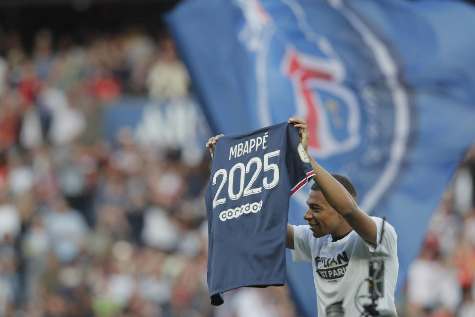 PSG's Kylian Mbappe waves a shirt to the crowd after it is announced that he has signed a three year extension to his deal to stay at the club ahead of the French League One soccer match between Paris Saint Germain and Metz at the Parc des Princes stadium in Paris, France, Saturday, May 21, 2022. (AP Photo/Michel Spingler)