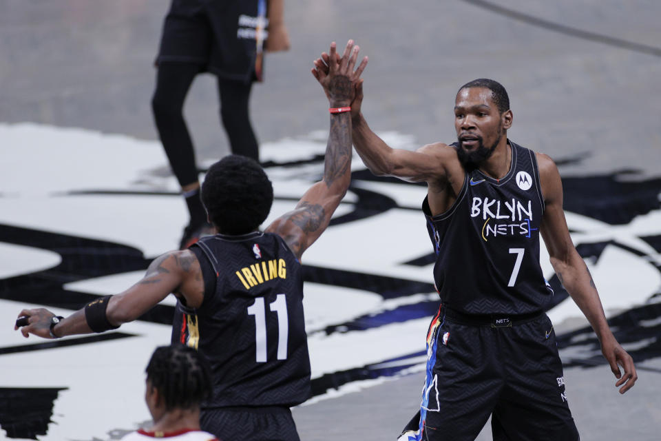 Kevin Durant (pictured right) and Kyrie Irving (pictured left) high-five during a game for the Brooklyn Nets.