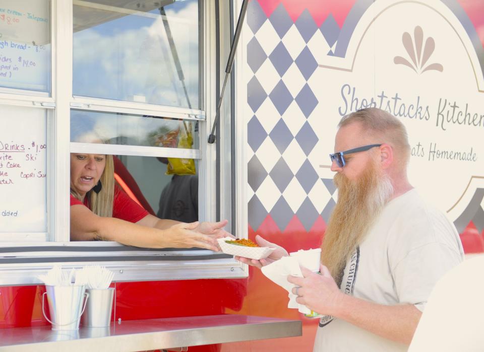 Pastor Brian DeTalente receives an order of loaded mac n cheese from Christa Chambers of Shortstacks Kitchen on Sunday, Sept. 10, 2023.