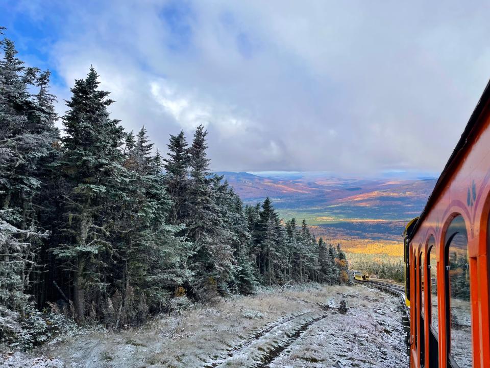 View of snowy mountains and fall foliage in valley below from train window