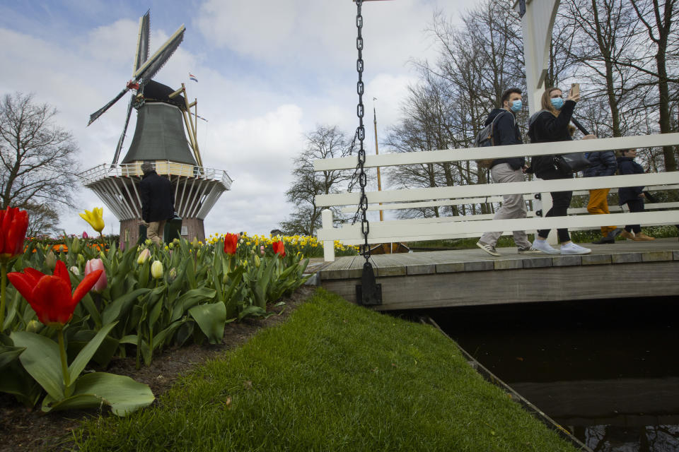 A couple wearing face masks take pictures at the world-famous Keukenhof garden in Lisse, Netherlands, Friday, April 9, 2021. Finally, after month after bleak month of lockdown, there are springtime shoots of hope emerging for a relaxation of coronavirus restrictions at a Dutch flower garden and other public venues. Keukenhof nestled in the pancake flat bulb fields between Amsterdam and The Hague opened its gates Friday to a lucky 5,000 people who were allowed in only if they could show proof on a smartphone app that they had just tested negative for COVID-19. (AP Photo/Peter Dejong)