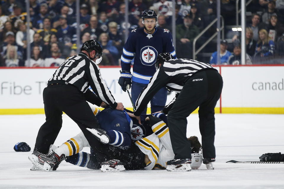 Winnipeg Jets' Anthony Bitetto (2) watches as Jets' Gabriel Bourque (57) and Boston Bruins' Brandon Carlo (25) fight during the second period of an NHL hockey game Friday, Jan. 31, 2020, in Winnipeg, Manitoba. (John Woods/The Canadian Press via AP)