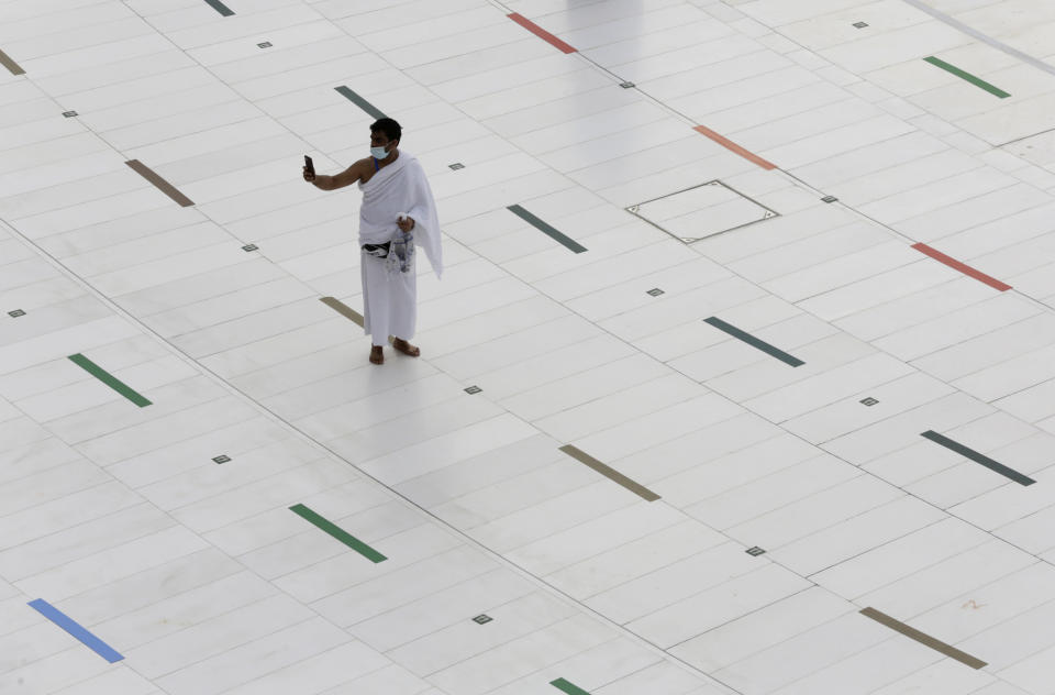 A Muslim pilgrim takes a selfie at the Grand Mosque, as he wears a mask and stands on social distancing signs, a day before the annual hajj pilgrimage, Saturday, July 17, 2021. The pilgrimage to Mecca required once in a lifetime of every Muslim who can afford it and is physically able to make it, used to draw more than 2 million people. But for a second straight year it has been curtailed due to the coronavirus with only vaccinated people in Saudi Arabia able to participate. (AP Photo/Amr Nabil)