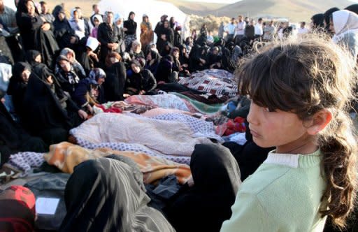 Iranians mourn over the covered bodies of loved ones in the village Baje-Baj, near the town of Varzaqan. Iran on Sunday stepped up relief operations in shattered villages in its northeast after saying rescue operations were completed following a double earthquake which cost 227 lives and injured 1,380 people