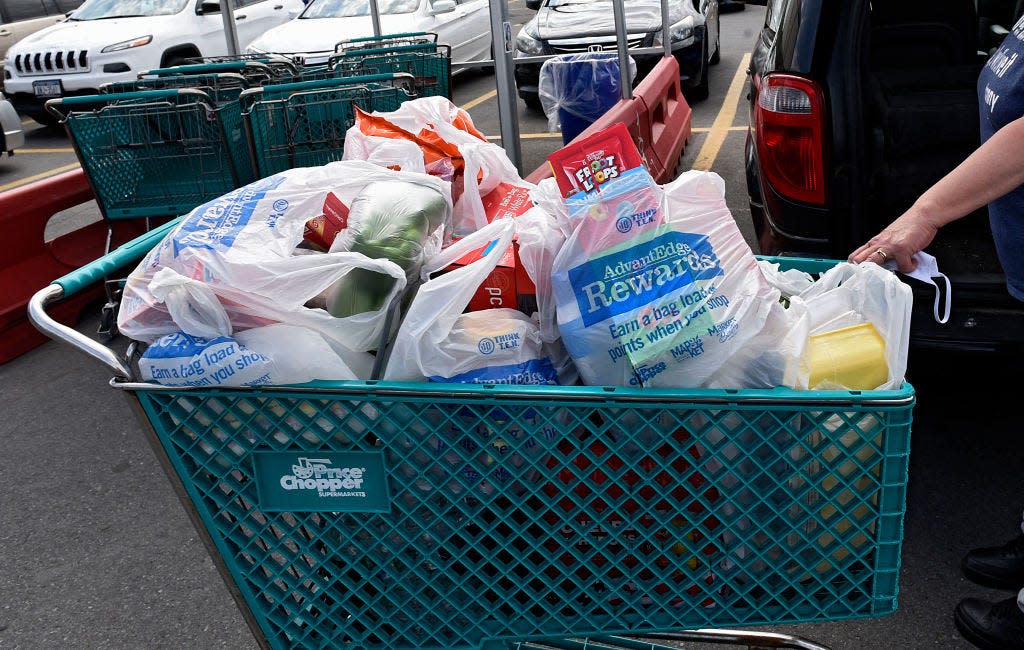 A shopping cart full of groceries in plastic bags