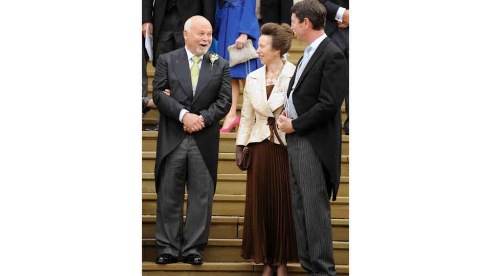 Princess Anne in a brown dress and white coat with Tim Laurence 