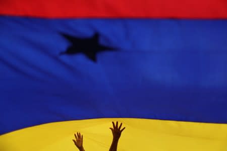 Locals hold a flag while Venezuelan opposition leader Juan Guaido, who many nations have recognised as the country's rightful interim ruler, takes part in a gathering with supporters in Caracas