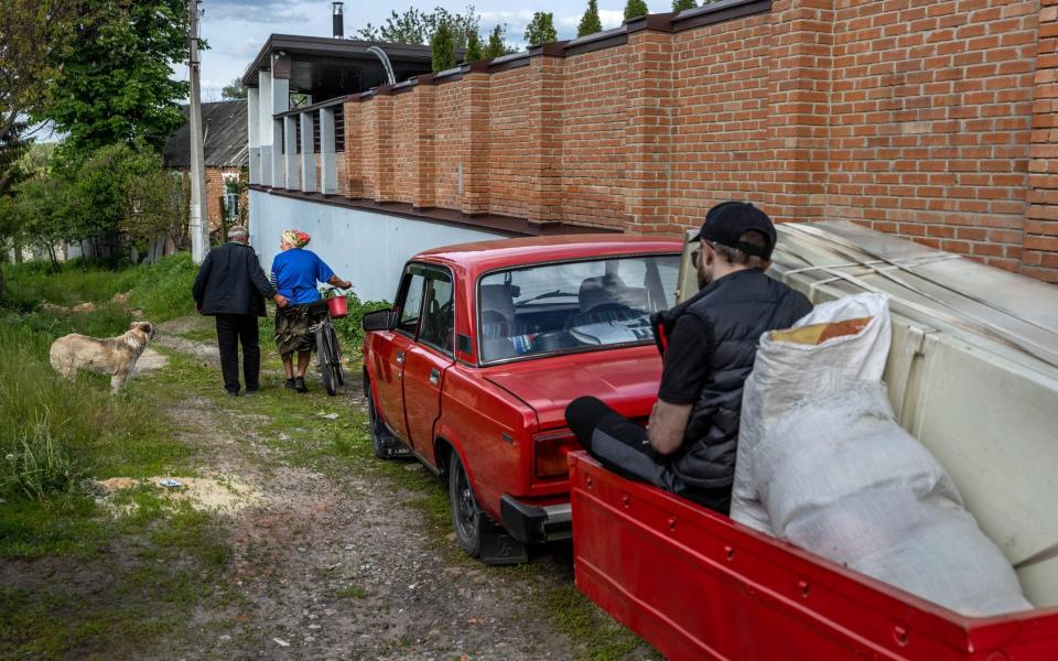 Kateryna Kostiantynivna walks with a neighbor to her shell-damaged home on May 24, 2022 in Kharkiv, Ukraine. She said three Russian shells hit her house the first week of the war. Although she has remained living in an adjacent family home, the neighborhood remains without electricity - John Moore/Getty Images