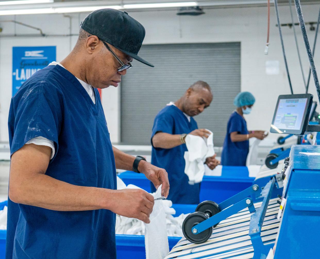 Lawrence Parker, from left, Michael Alexander and Rosalyn Burch run linens through an automatic folder at the Goodwill's James O. Wright Center for Work & Training in Milwaukee. It has one of the largest laundry facilities in Wisconsin, providing services for hospitals, clinics, nursing homes and the military throughout the state and northern Illinois.