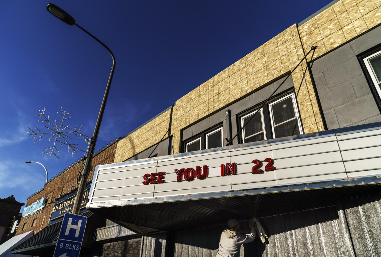 A worker polishes a marquee at a theater under renovation in Benson, Minn., Monday, Nov. 29, 2021. It can be easy, looking around Benson, to think it is a land that time forgot. Bartenders often greet customers by name. Many farms and businesses have been owned by the same families for decades: through the droughts of the 1930s; through the thriving years around World War II; to the population decline that began in the 1950s. But plenty has changed. (AP Photo/David Goldman)