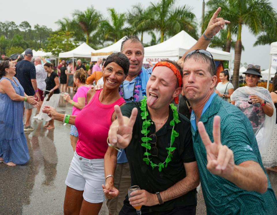 People dance in the rain during the USA Today Wine and Food Experience at Paradise Coast Sports Complex in Naples on Saturday, Sept. 30, 2023.