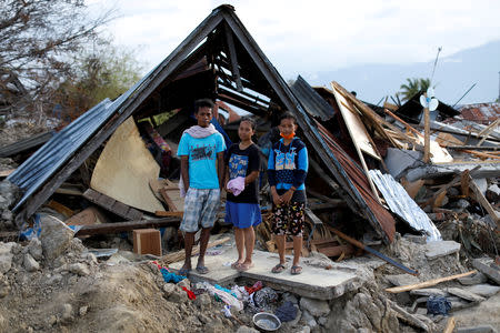 Muhammad Nur, 27, his wife Nita Puspita, 25 and Nita's sister Widya Wijayanti, 14, stand in front of their former home, obliterated by ground liquefaction looking for useful items, in Petobo neighbourhood, Palu, Central Sulawesi, Indonesia, October 11, 2018. REUTERS/Jorge Silva