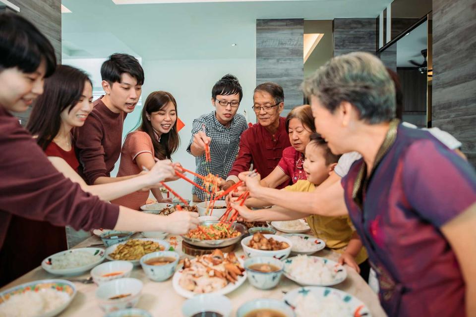 Family celebrating lunar new year's eve with raw fish salad Lou Shang during reunion dinner