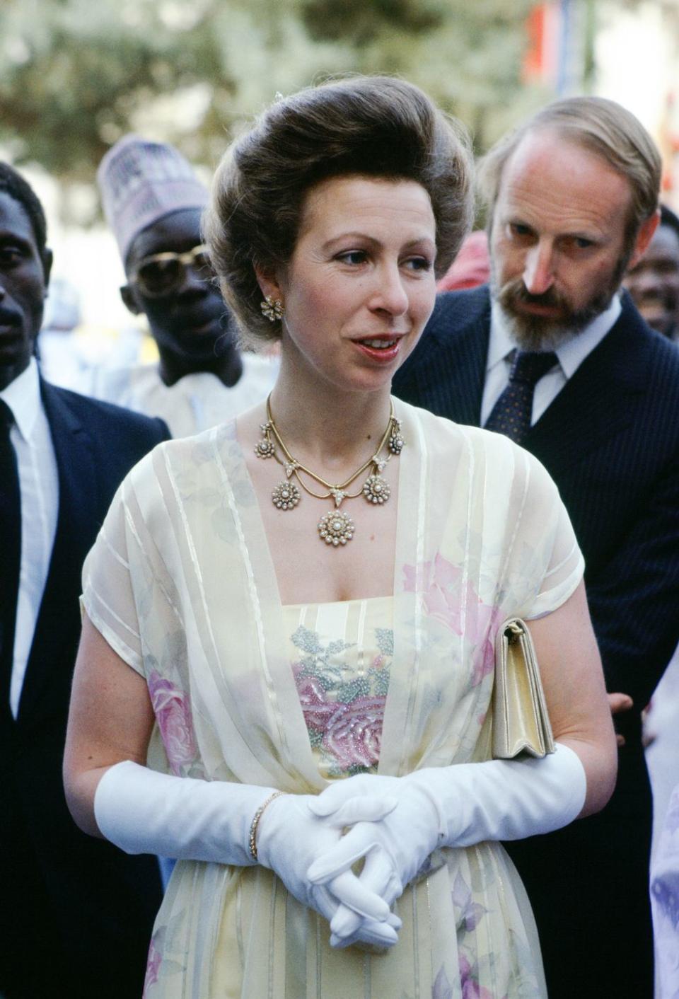 <p>During a tour of the Gambia with Save the Children in 1984, Princess Anne complemented her pale yellow frock with a gold necklace embellished with pearls, plus glittering floral earrings.<br></p>