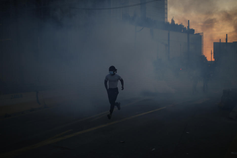 A protesters runs through tear gas during a demonstration Tuesday, June 2, 2020. Paris riot officers fired tear gas as scattered protesters threw projectiles and set fires at an unauthorized demonstration against police violence and racial injustice. Several thousand people rallied peacefully for two hours around the main Paris courthouse in homage to George Floyd and to Adama Traore, a French black man who died in police custody. (AP Photo/Rafael Yaghobzadeh)