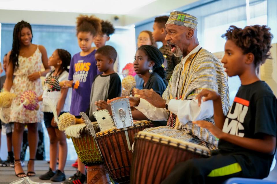 Jun 18, 2022; Tempe, Ariz., U.S.;  Percussionist Keith Johnson leads an African Djembe Drums & Stories session with children playing shakers and drums alongside him.