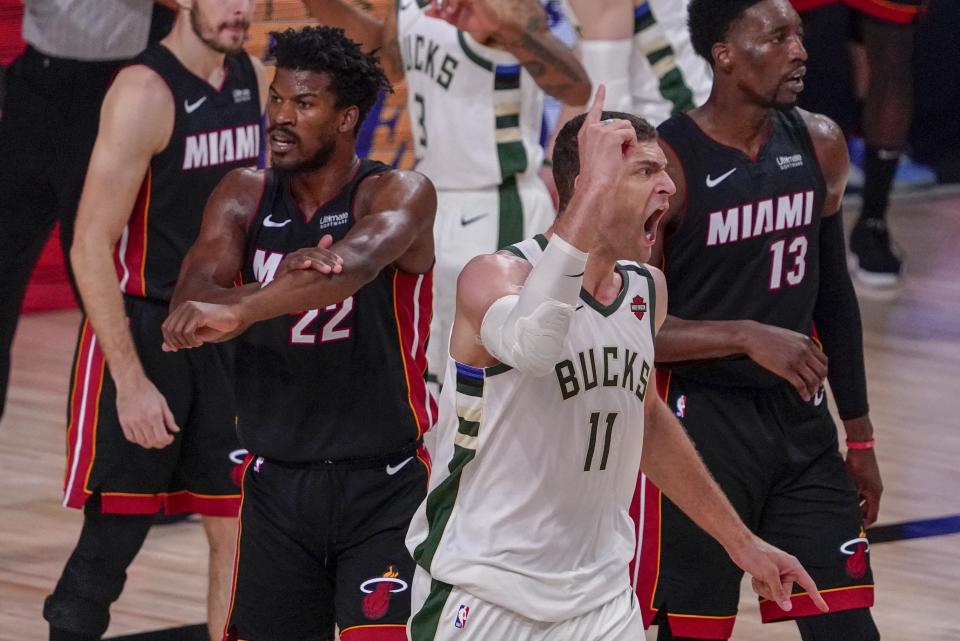 Milwaukee Bucks' Brook Lopez and Miami Heat's Jimmy Butler react to a call during the second half of an NBA conference semifinal playoff basketball game Sunday, Sept. 6, 2020, in Lake Buena Vista, Fla. (AP Photo/Mark J. Terrill)