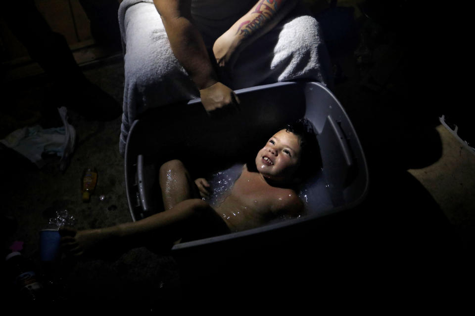 Tasha Hughes, bathes her daughter, Madison, 4, in a storage bin outside their room at the damaged American Quality Lodge where they continue to live without power in the aftermath of Hurricane Michael, in Panama City, Fla., Tuesday, Oct. 16, 2018. Simply getting through the day is a struggle at the low-rent motel where dozens of people are living in squalor amid destruction left by the hurricane. (AP Photo/David Goldman)