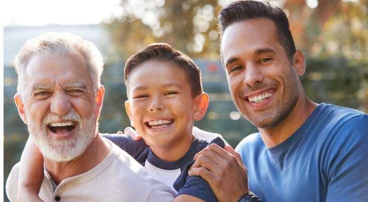 portrait-of-multi-generation-txiv neej-haiv neeg-tsev neeg-hauv-garden-smiling-at-camera-SmartAsset-Sandwich-Generation