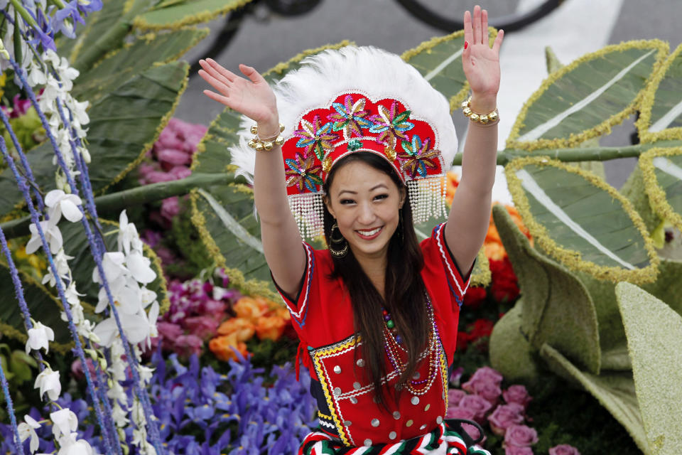 A woman waves from the "Cycling Through Paradise" float by China Airlines, winner of the International trophy for the most beautiful entry from outside the United States, in the 124th Rose Parade in Pasadena, Calif., Tuesday, Jan. 1, 2013. (AP Photo/Patrick T. Fallon)
