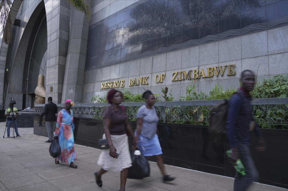People walk past the Reserve Bank of Zimbabwe following the introduction of the country's new currency at a press briefing in Harare, Friday, April 5, 2024.Zimbabwe on Friday launched a new currency to replace a local unit that in recent months has been battered by depreciation, and in some instances rejected by the population, and authorities hope the new measure will arrest the currency crisis underlining the country's years long economic troubles. (AP Photo/Tsvangirayi Mukwazhi)