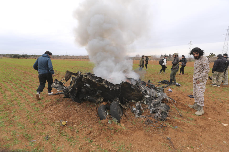 Rebel fighters look at a Syrian government helicopter that was shot down in Idlib province, Syria, Tuesday, Feb. 11, 2020. Syrian rebels shot down a government helicopter Tuesday in the country's northwest where Syrian troops are on the offensive in the last rebel stronghold. (AP Photo/Ghaith Alsayed)