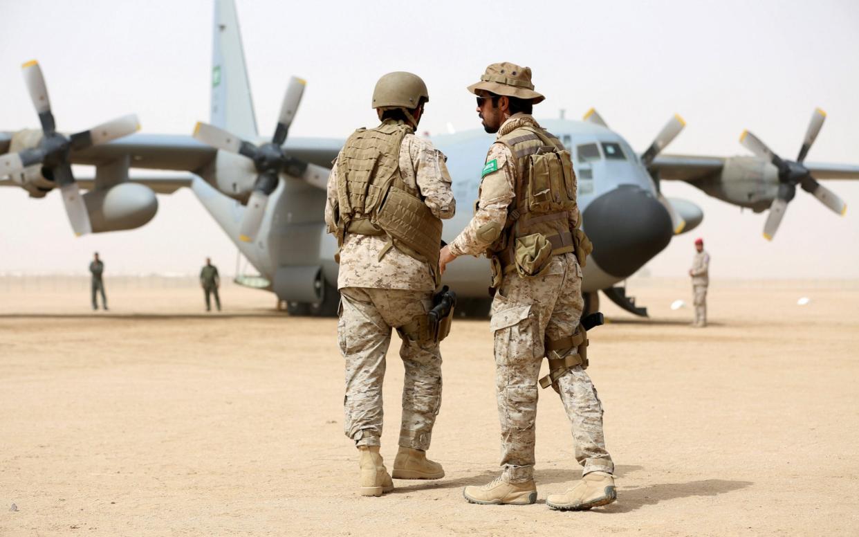 Saudi soldiers walk past a Saudi air force cargo plane delivering aid at an airfield in the northern province of Marib in Yemen - REUTERS