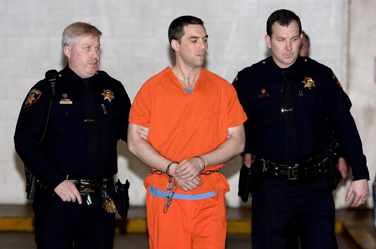 Convicted murderer Scott Peterson is escorted by two San Mateo County Sheriff deputies as he is walked from the jail to an awaiting van March 17, 2005, in Redwood City, California.