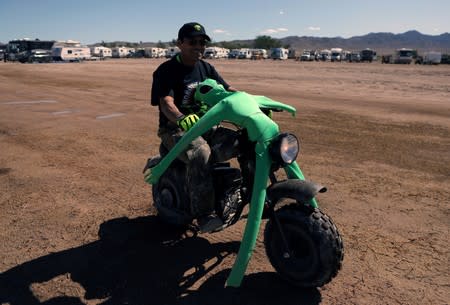 A man rides a motorcycle with an alien doll strapped to it as an influx of tourists responding to a call to 'storm' Area 51, in Rachel, Nevada