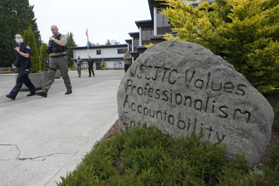 Cadets LeAnne Cone, left, of the Vancouver Police Dept., and Kevin Burton-Crow, right, of the Thurston Co. Sheriff's Dept., walk past a rock at the Washington state Criminal Justice Training Commission engraved with "WSCJTC Values Professionalism, Accountability Integrity," on the way to a training exercise Wednesday, July 14, 2021, in Burien, Wash. Washington state is embarking on a massive experiment in police reform and accountability following the racial justice protests that erupted after George Floyd's murder last year, with nearly a dozen new laws that took effect Sunday, July 25, but law enforcement officials remain uncertain about what they require in how officers might respond — or not respond — to certain situations, including active crime scenes and mental health crises. (AP Photo/Ted S. Warren)