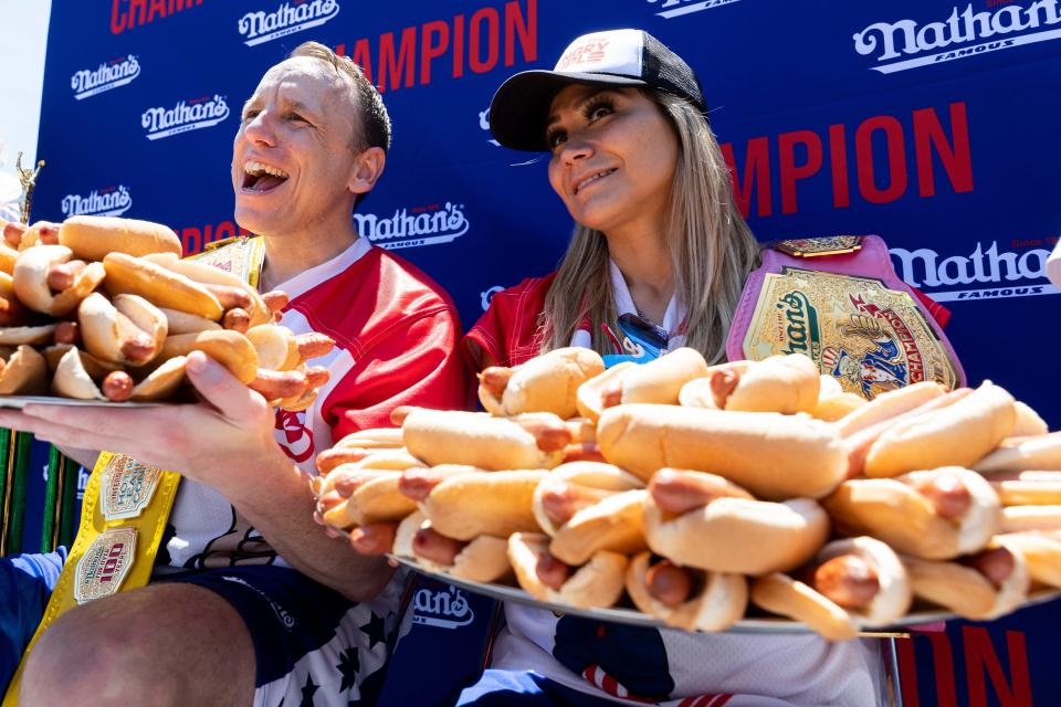 Joey Chestnut, left, and Miki Sudo pose with 63 and 40 hot dogs, respectively, after winning the 2022 Nathan's Famous Fourth of July hot dog eating contest.